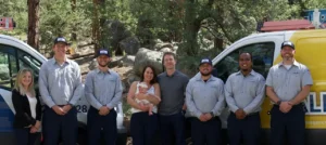Allied Electric Team standing in front of work vehicles with beautiful background